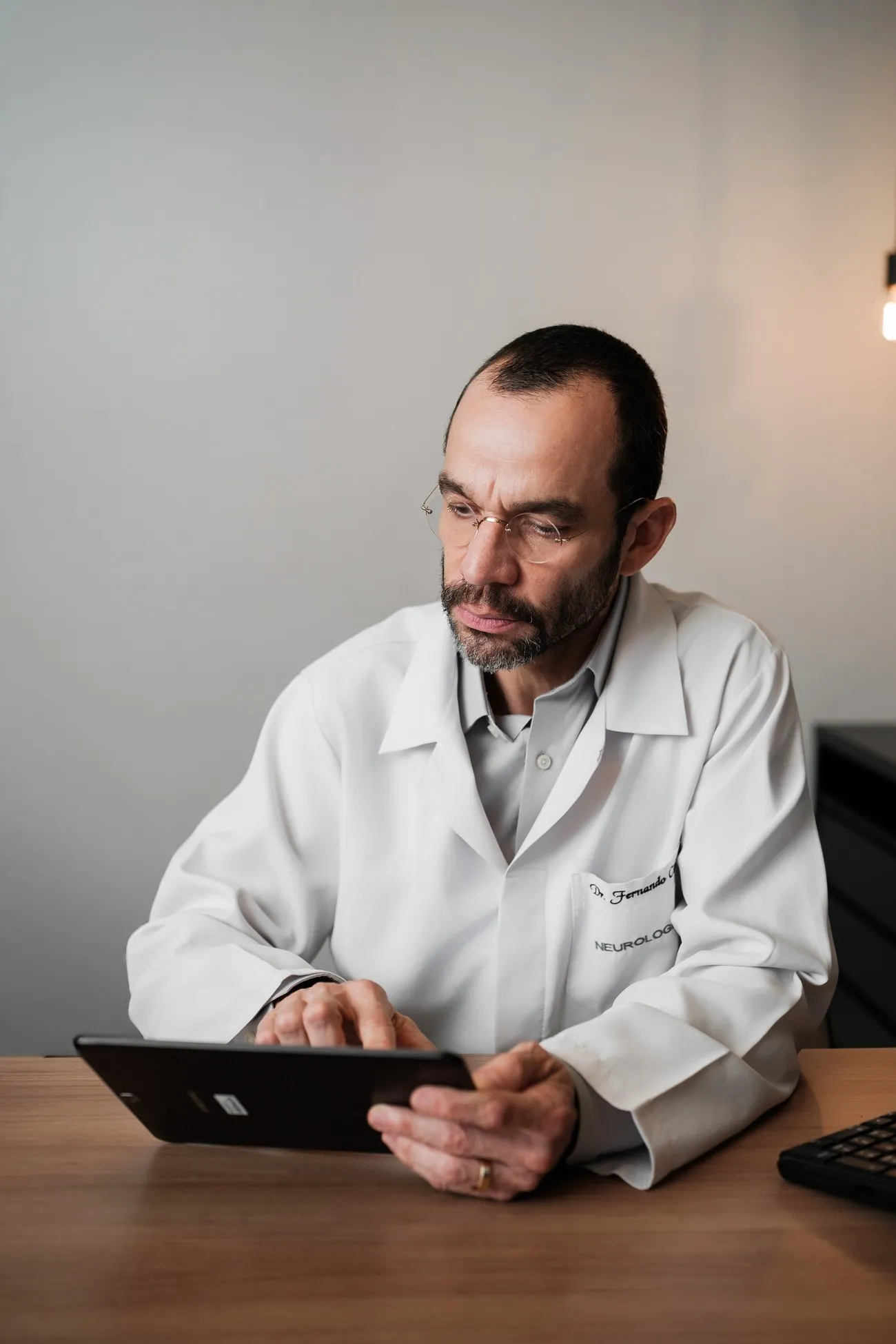 Dr. Fernando Cini Freitas revisando exames em um tablet durante o atendimento
